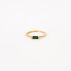 The Empire Emerald Ring features a rectangular emerald center flanked by small clear stones on a classic gold band, shown on a white background.