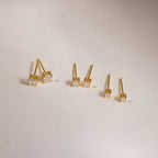Three pairs of Booker Tiny Diamond Studs in 4mm, 3mm, and 2mm sizes rest on a neutral background—perfect minimalist gold earrings for everyday subtle sparkle.