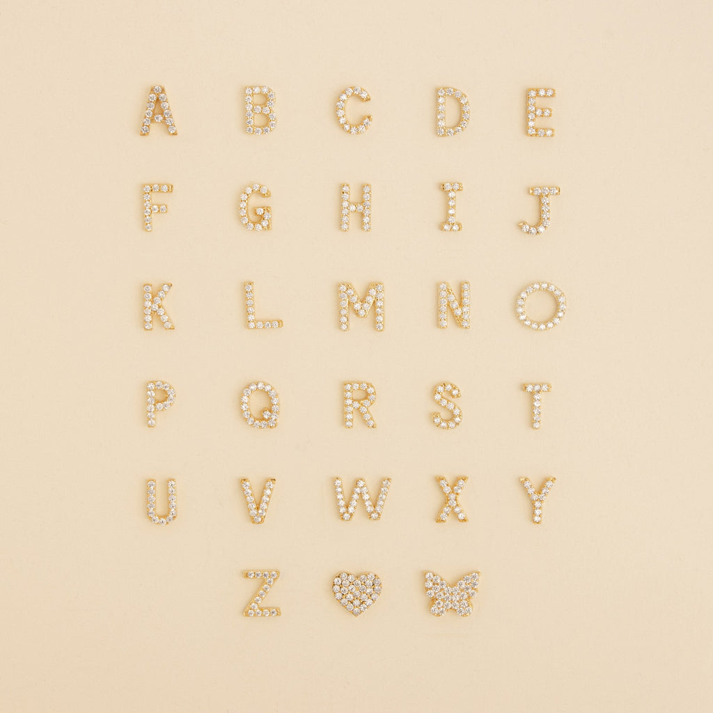 The Pave Initial Heart Necklace features gold, diamond-studded alphabet letters and a heart charm—ideal for creating your own custom initial or handmade diamond necklace.