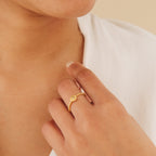 A hand adorned with the Eden Sun Ring rests near the chin, as the person wears a white top.