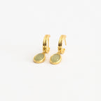 Pair of gold hoop earrings with oval jade gemstone drop pendants displayed on a clean white surface, showcasing a modern and dainty jewelry style.