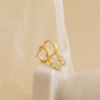 Gold huggie hoop earrings with oval jade gemstone charms displayed on a soft mesh fabric, highlighting their refined and minimalist aesthetic.