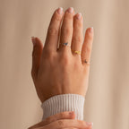 A hand with manicured nails wears three delicate rings, including the Pet Initial Ring—an elegant, personalized jewelry piece perfect for pet lovers.