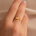 A Duo Pet Initial Ring featuring a gold cat and letter G design on a finger, close-up on a neutral background—the ideal personalized jewelry for animal lovers.