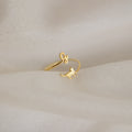 The Duo Pet Initial Wrap Ring showcases a cat and cursive "G" design, displayed on soft beige fabric—an ideal personalized jewelry piece for cat lovers.