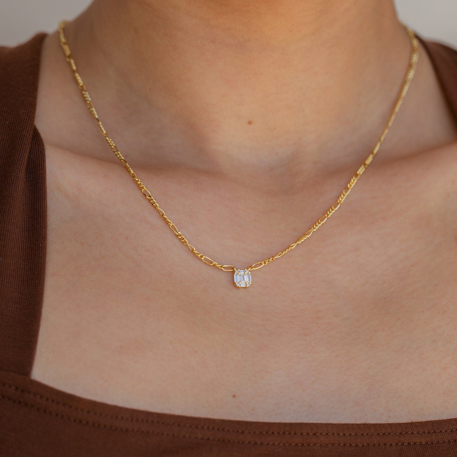 A Square Diamond Figaro Necklace featuring a sparkling square diamond pendant, stylishly worn around the neck.