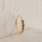 The Flower Bar Ring in Rose Gold features an engraved daisy and bud, standing upright against a textured light surface—a perfect botanical jewelry piece for nature lovers.