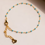 The Turquoise Station Bracelet features a gold chain with small turquoise beads and a heart charm—perfect for stacking with your other bracelets.
