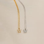 The Mandy Pave Butterfly Necklace features gold or silver pendants adorned with sparkling crystals and delicate diamond accents, beautifully displayed on a light textured fabric background.