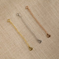 The Chain Extender in Sterling Silver is displayed on a beige fabric background—perfect to personalize jewelry or adjust necklaces and bracelets for the ideal fit.