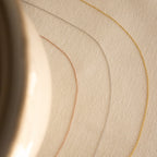 The Dainty Chain Necklace, shown in gold, silver, and rose gold, curves across a beige textured surface with a blurred object to the left for a refined minimal look.