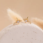 The Starry Night Ear Cuffs are gold, star-shaped cuffs with small crystals, elegantly displayed on a textured white stone and soft beige background. These no-piercing earrings add a sparkling touch to any look.