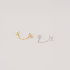 The Luna Moon & Star Chain Earrings feature two pairs—one gold, one silver—linked by delicate chains, ideal for adding celestial style to your cartilage piercing. Shown on a light background.
