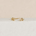 Dainty jewelry lovers will adore the Tiny Python Studs—petite gold earrings with elegant curves, perfect for a boho-luxe style and shown on a white textured background.