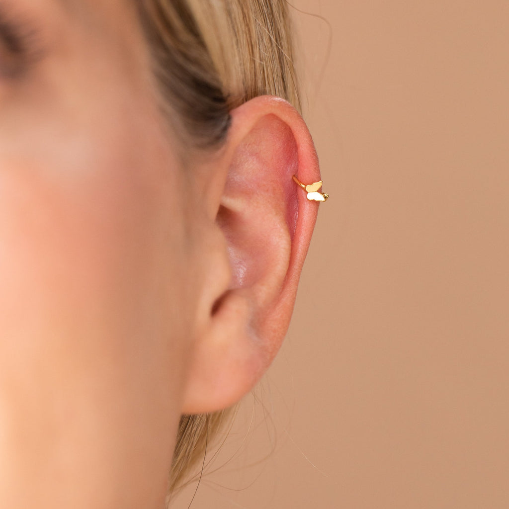 Close-up of dainty butterfly huggie hoop highlighting fitted clasp around ear.
