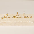 Five Constellation Earrings rest on a light stone surface, illuminated by soft lighting and inspired by astrology.