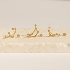 Five Constellation Earrings rest on a light stone surface, illuminated by soft lighting and inspired by astrology.