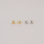 Two pairs of Starburst Studs—one gold, one silver—each adorned with a small central gem, reminiscent of diamond earrings, shown on a plain background.
