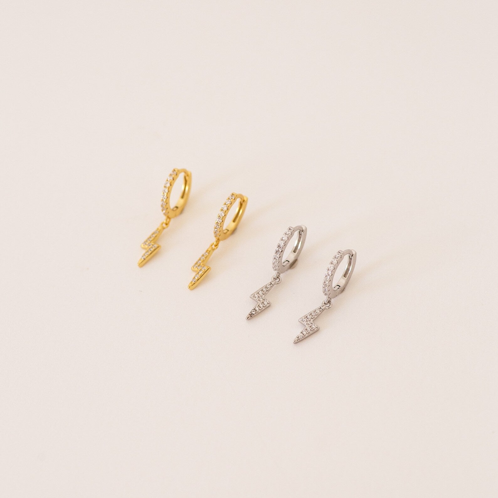 The Striker Pave Huggies, available in gold and silver lightning shapes, add a bold, trendy touch to any look—perfect for electrifying your style.