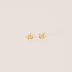 Tiny Python Studs: Small gold snake-shaped earrings that bring a boho-luxe accent to any outfit. Featured on a minimalist light background.