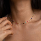 A close-up of a woman wearing the Rainbow Station Necklace, a delicate piece featuring small, colorful beads around her neck.