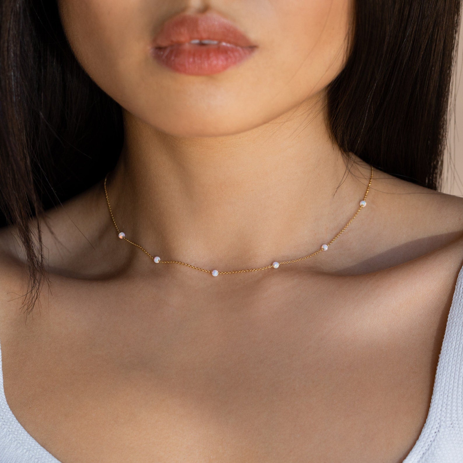 Woman wearing the Opal Station Necklace, a delicate and minimalist piece featuring small opals, shown from shoulders up in natural light.