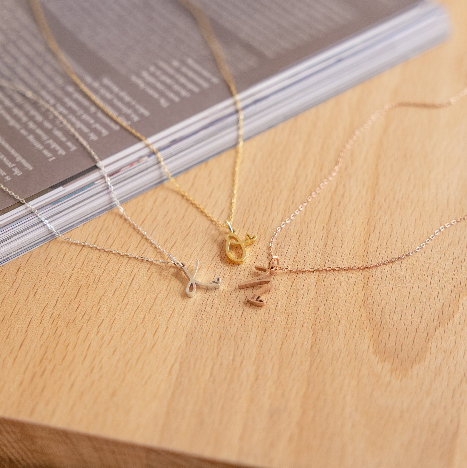 A group of necklaces on a table, including the Letter Heart Necklace and a minimalist everyday necklace, perfect for adding a personalized touch to any look.