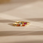 Two Duo Baguette Birthstone Rings with rectangular red, orange, and clear stones rest on a soft beige surface—an elegant personalized gift from the Duo Baguette Birthstone Ring collection.