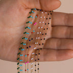 A hand holds delicate gold Beaded Station Necklaces with colorful beads, highlighting trendy styles perfect for playful jewelry lovers.