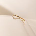 The Marquise Birthstone Ring, featuring a delicate design and a small diamond, rests on a glossy surface with a soft shadow, showcasing its elegant charm.
