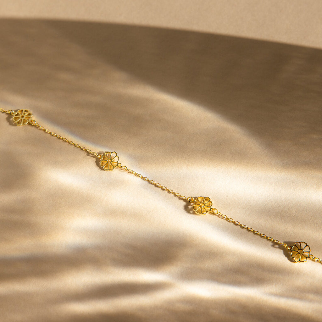 Elegant gold Flower Station Necklace with floral charms on a soft, golden satin background—perfect floral jewelry and a thoughtful gift for her.