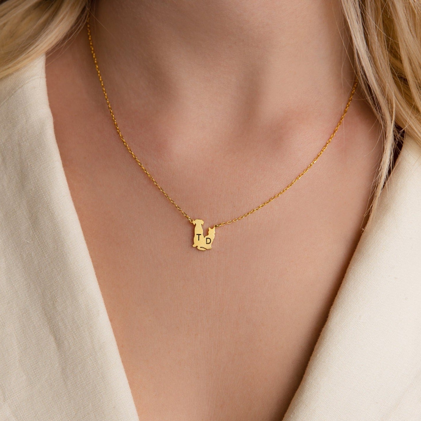 Close-up of a woman wearing the Pet Initial Necklace with T and D charms on a cream blouse—a personalized accessory and perfect gift for pet lovers.