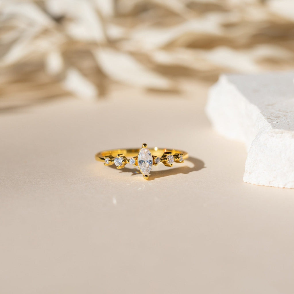 The Harlow Diamond Ring, featuring five sparkling diamonds, is presented on a neutral background. This vintage eternity ring radiates timeless elegance with its classic design and softly blurred surroundings.