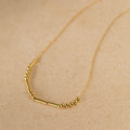 Morse Code Necklace with small round and tube-shaped beads on a delicate chain, shown on a beige surface—makes a unique, personalized gift.