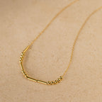 Morse Code Necklace with small round and tube-shaped beads on a delicate chain, shown on a beige surface—makes a unique, personalized gift.