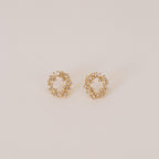 The Reina Cluster Studs are gold circular earrings featuring baguette-cut stones in a wreath-like pattern, making them the perfect elegant bridal accessory for your special day.