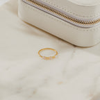 Alessia Trio Opal Ring in gold displayed on a marble surface beside a cream jewelry case, showcasing its opals and diamond accents.