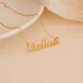 The Maine Kid's Name Necklace, customized with the name Stella and a small star charm at the end, is shown on a beige surface.
