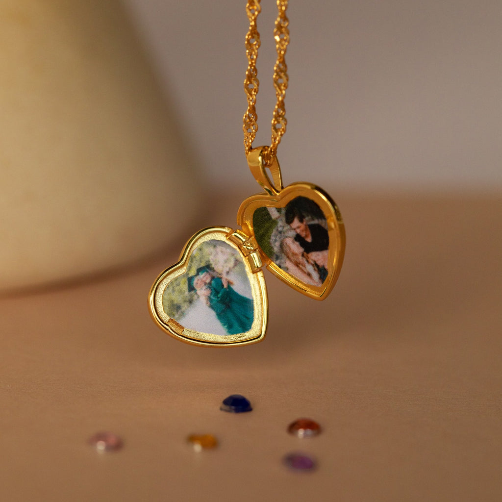 The Initial Heart Locket Necklace is a gold, heart-shaped locket that opens to hold two small photos, perfect as personalized jewelry for couples.
