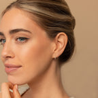 A woman with light eyes and smooth skin wears the elegant Amaya Marquise Threaders, looking thoughtful against a beige background.