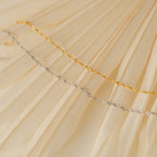 The Singapore Twist Bracelet, featuring a gold and silver twisted rope design, is displayed on a cream-colored pleated fabric background.