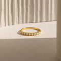 The Crescent Opal Ring features small oval opal stones set in gold, beautifully displayed on a textured white surface with soft shadows—an elegant promise ring or thoughtful anniversary gift.