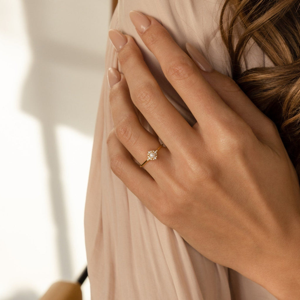 A woman’s hand with nude nails rests on her shoulder, wearing the Vintage Pave Pearl Ring in 18K Gold—an elegant accessory and a sophisticated choice for a Christmas gift.