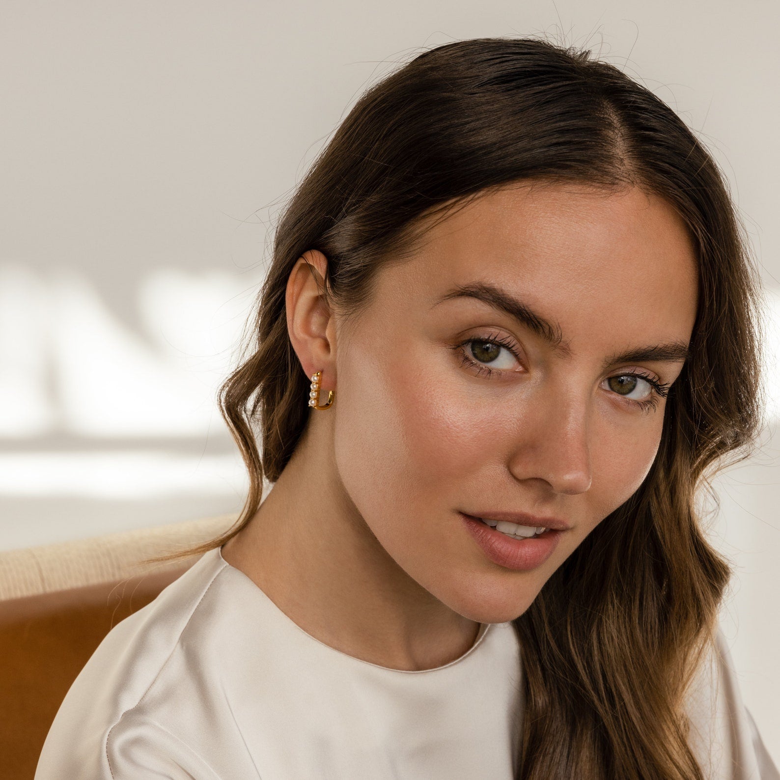 A woman with long hair wearing a white shirt and Rayne Pearl Link Earrings.