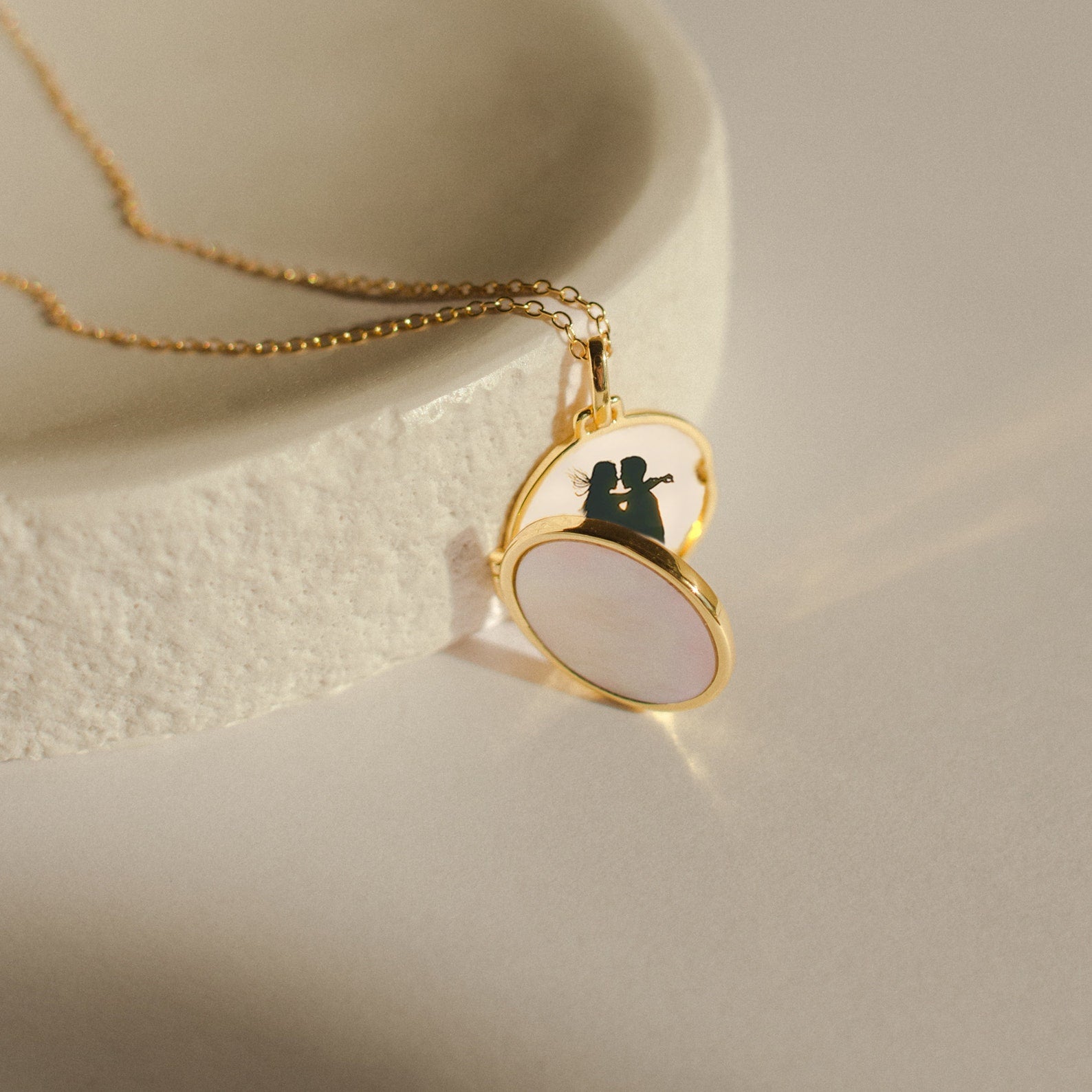 Pearl Disc Locket Necklace displayed on a textured white surface, featuring a silhouette photo inside—an elegant and meaningful gift.