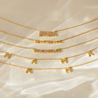 Five gold Mama Necklaces in different fonts and styles lie on a satin-like surface—an ideal gift for Mom that brings a heartfelt touch to her jewelry collection.