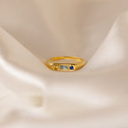 The Bold Birthstone Signet Ring in Rose Gold showcases three customizable gemstones, displayed on soft white fabric.