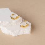 Mellow Name Earrings spelling "earlier" are displayed on stacked white stone slabs with a beige backdrop—ideal for a custom gift or personalized keepsake.