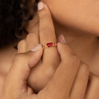 A hand wearing the Space Baguette Birthstone Ring with a rectangular red gemstone, finger touching the chin.