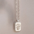 The Ribbed Flower Tag Necklace features a rectangular, flower-engraved pendant and vintage-inspired style—ideal for adding everyday charm.